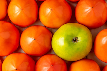 Juicy persimmons and green apple on a wooden background.