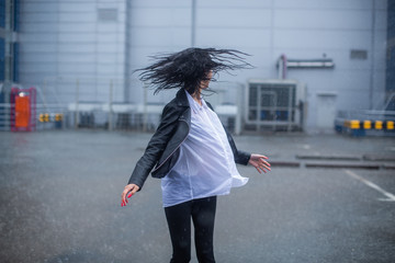 Slender girl dancing and spinning in the pouring rain.
