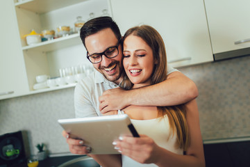 Young couple using digital tablet in the kitchen