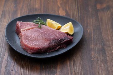 raw tuna with salt and lemon on dark plate
