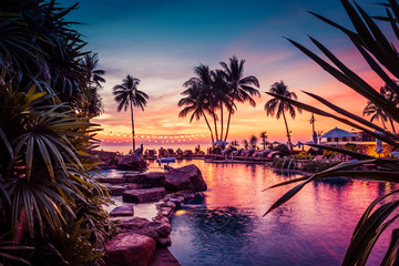 Atemberaubende Aussicht auf den Sonnenuntergang mit Palmen, die sich im Pool im luxuriösen Inselresort in Thailand widerspiegeln?