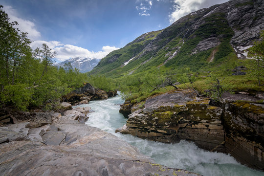 Wild river with heavy current raging down in green mountain landscape Norway