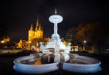 Beautifully decorated historic fountain with an old city gate in the background