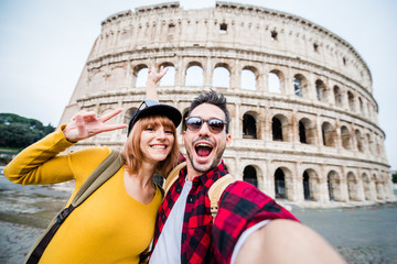 Happy couple of tourist smiling and taking a selfie at the Colosseum in Rome.