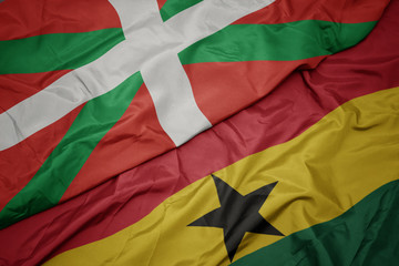 waving colorful flag of ghana and national flag of basque country.