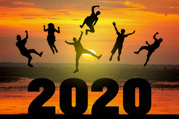 Silhouette of friends jumping celebrating new year over number 2020 on blurred sunrise background, Happy New Year celebration concept