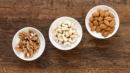 Walnüsse, Cashewkerne und Mandeln in Schüsseln auf altem Holz