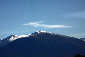 View over snow-covered mountain peak against blue sky