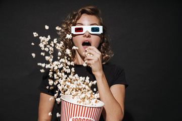 Concentrated cute young woman eat popcorn watch cinema.