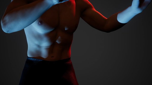Handsome muscular shirtless young man standing in the dark