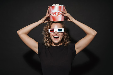Happy young woman in 3d glasses holding popcorn.
