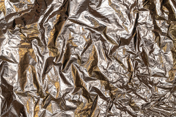 Silver foil background with shiny crumpled surface for textured background.