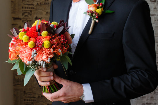 Red roses wedding bouquet in hands of the grrom