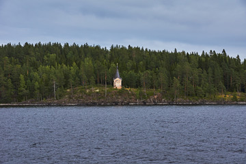 A lonely Orthodox chapel in a forest on the shore of Lake Ladoga on the island of Valaam. The hipped roof and cross on the dome are visible. Russia, Karelia.Orthodox chapel