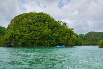 Fototapeta na wymiar Boat anchored close to exotic tropical island. Panoramic landscape view of Los Haitises natural park,Samana peninsula in Dominican republic.