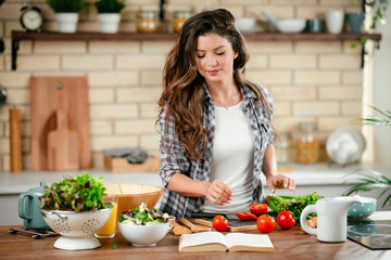 Young woman in kitchen. Beautiful woman making salad. 