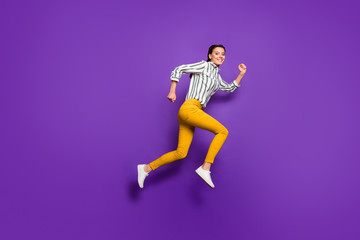 Fototapeta na wymiar Full length profile photo of crazy beautiful lady jumping high rushing discount prices shopping wear striped shirt yellow trousers isolated purple color background