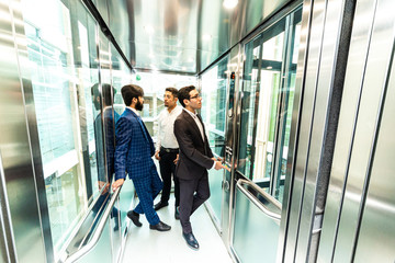 Business team group going on elevator. Business people in a large glass elevator in a modern office. Corporate businessteam and manager in a meeting.