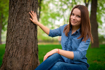 pretty young female sits on a ground in the park