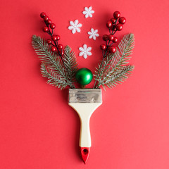 Flat lay of paint brush with christmas tree branches, bauble decoration, snowflakes and red berries...