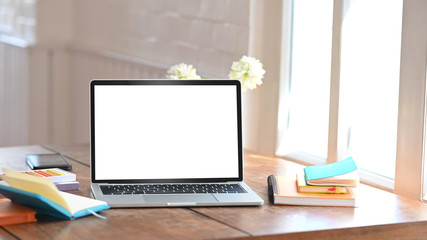 Mockup laptop computer isolated white screen on creative workspace.