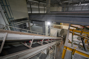 The conveyor belt of ingredients to the mixer. Workers in the workshop of the House-building plant. Industrial interior. Concrete plant.