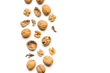 top view of walnuts closed and broken scattered on a white background with copy space
