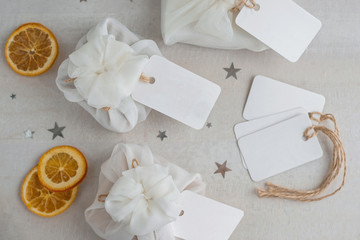 Christmas presents wrapped with white furoshiki fabric, labels and dried orange slices. Eco friendly gift.