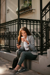 Obraz na płótnie Canvas Beautiful businesswoman on coffee break using phone. Young businesswoman outdoors. 
