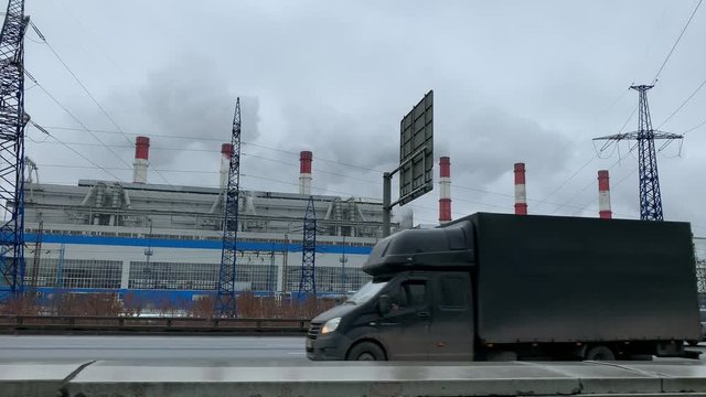 Factory with smoking chimneys near a highway in city limits. Close-up