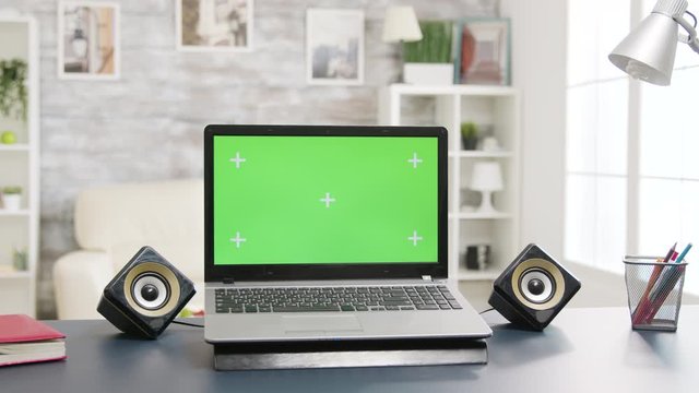 Laptop with green screen on the table in bright and well lit living room space
