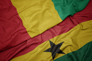 waving colorful flag of ghana and national flag of guinea.