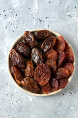 Dried dates and plums on a gray background