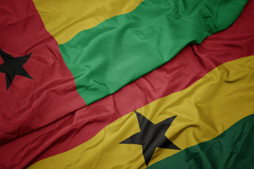 waving colorful flag of ghana and national flag of guinea bissau.