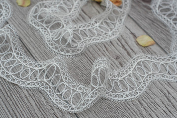 White wooden background with white spring flowers roses and lace ribbon. Happy womans day. The texture of lace on wooden background.