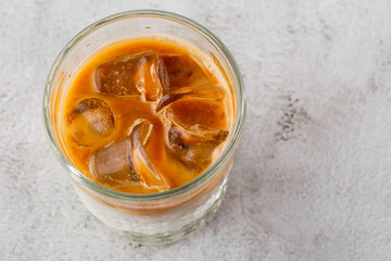 Glass with cold brew coffee and milk isolated on bright marble background. Overhead view, copy space. Advertising for cafe menu. Coffee shop menu. Horizontal photo.