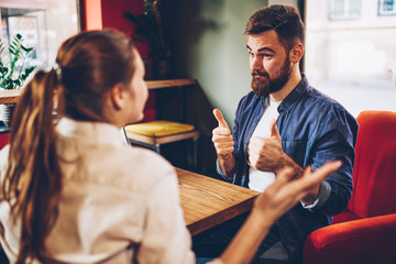 Bearded young man with thumb up praise female colleague for productive idea for developing common startup project.Two creative designers discussing successful plan of collaboration during meeting