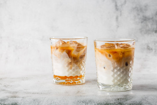 Two glasses with cold brew coffee and milk isolated on bright marble background. Overhead view, copy space. Advertising for cafe menu. Coffee shop menu. Horizontal photo.