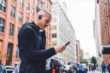 Naklejka premium Man in city street choosing music on phone