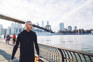 Fit male runner standing on city promenade