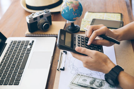 Close Up The Hands Of Travelers Using A Calculator To Calculate Travel Expenses. Planning A Trip,copy Space. Travel Background