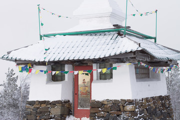 Buddhist stupa temple with snow on the roof on a frosty winter day