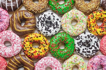 Background with colorful sweet cakes. Donuts with a hole with different toppings and decorations.