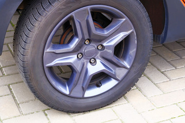 Car wheel, close up. Auto is parked in its parking spot in city.