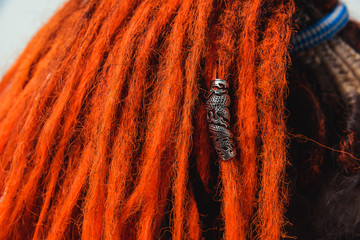 Red fiery natural dreadlocks and pigtails with decorations on white. Orange dreadlocks and close-up...