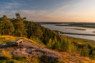 Bench with mountain views of the coniferous forest and lake. Sunset on Mount Paaso. Karelia