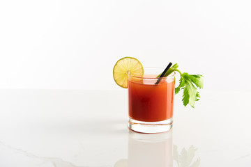 bloody mary cocktail in glass garnished with lime and celery isolated on white
