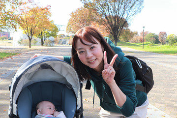 秋の公園を散歩するママと赤ちゃん