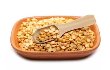 Split peas in clay pot, bowl with wooden spoon isolated on white background