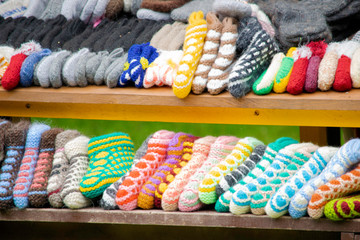 handmade multi-colored knitted socks and slippers lie on the window of the street market